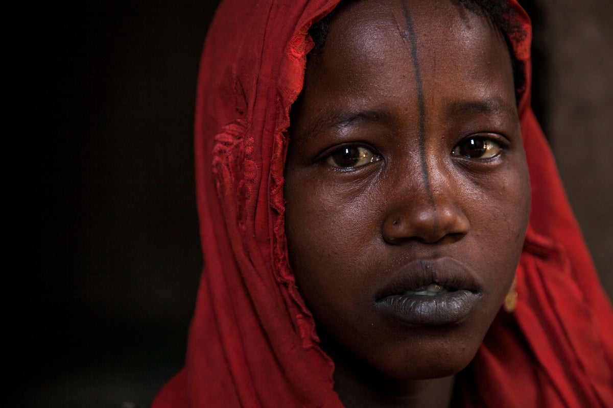 A young girl is looking at the camera. She looks sad.