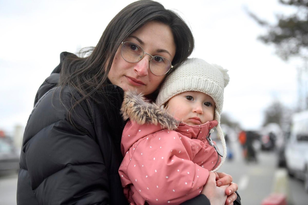 A woman is hugging a toddler girl and they are both looking at the camera with sadness