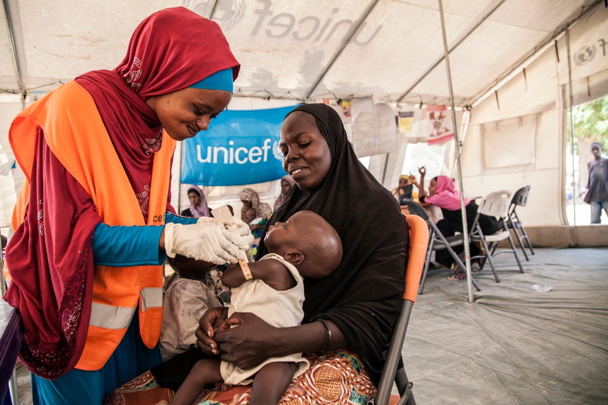 A health worker screens a baby for malnutrition
