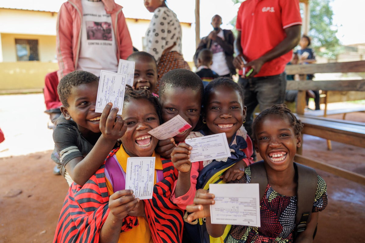 A group of young kids hold up their vaccination certificates