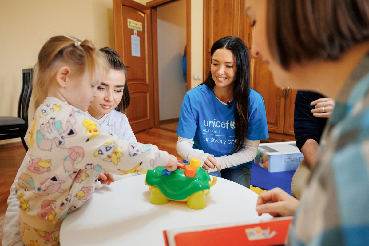 A woman watching a young girl participating in occupational therapy.