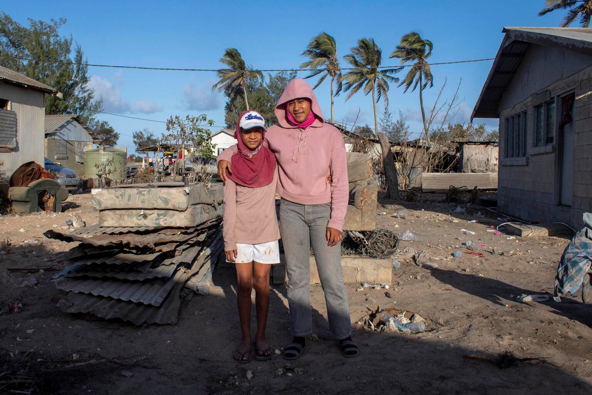 A boy and a young woman look at the camera. Behind them looks like they've been cleaning up.