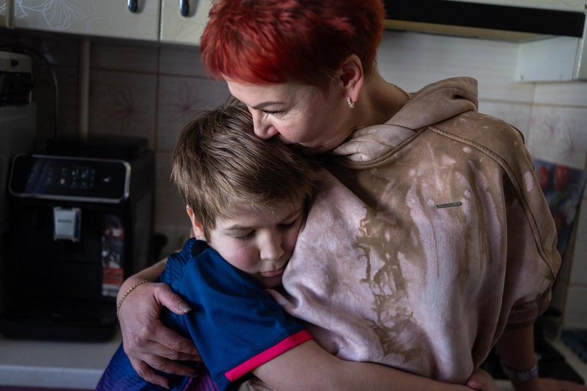 In Ukraine, 10-year-old Andrii embraces his mother in their kitchen. After losing his father last winter, Andrii has had to navigate life without him. 