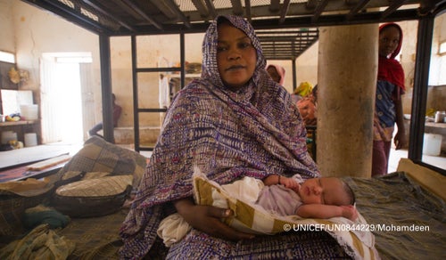 Hawa cuddles her newborn. She delivered her baby at the temporary shelter after her family was displaced by conflict. 