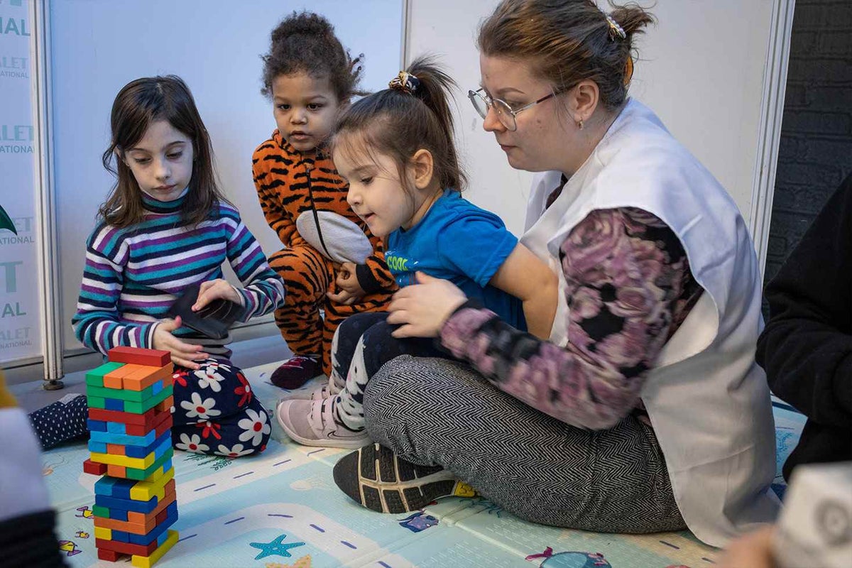 A social worker plays with Ukrainian refugee children at a UNICEF-supported Blue Dot in Moldova. This safe space has been set up for little ones to play and be children again.