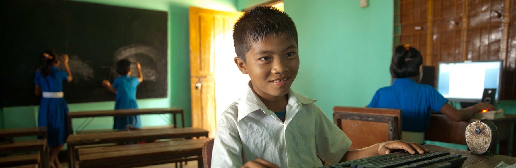 Young boy in a classroom smiling at the camera