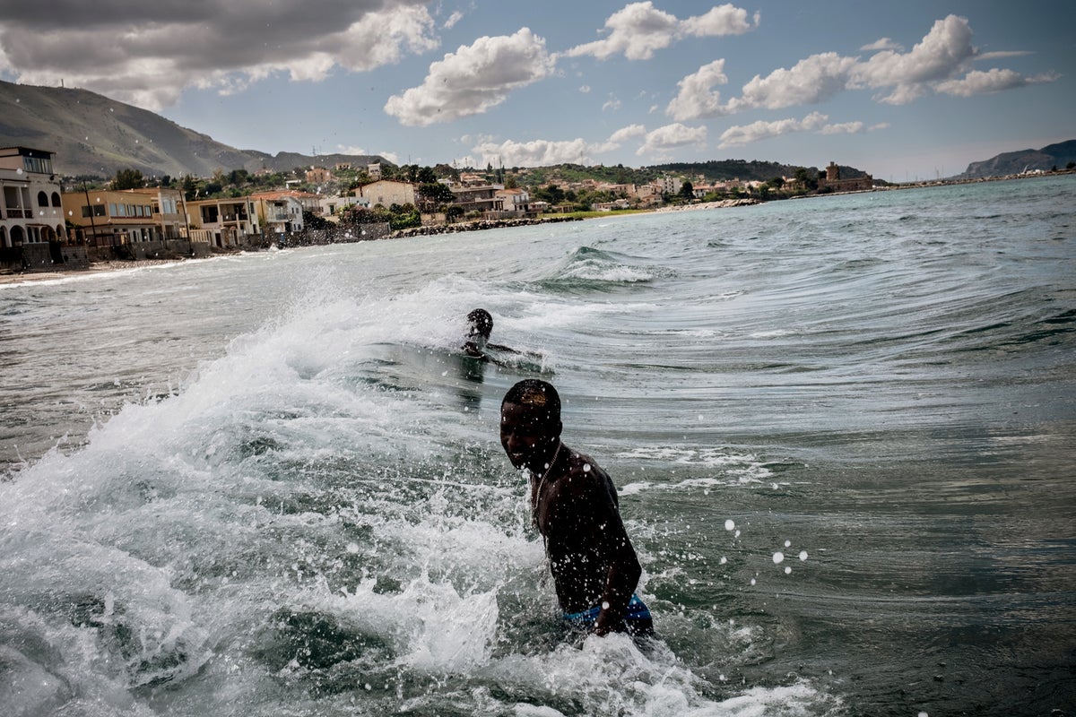 Two teenage boys in are swimming on a beach.