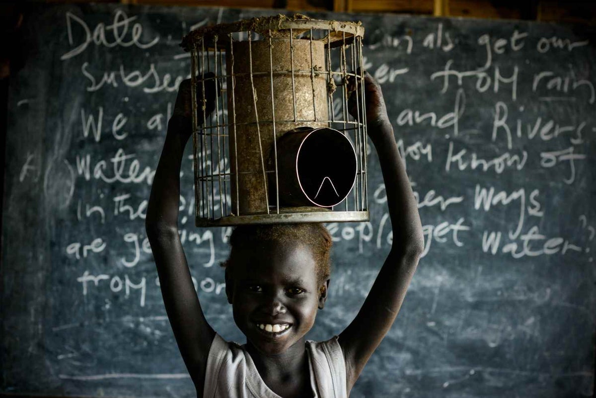 Six year-old Nyaboth holds her family stove that she carries to school to sit on during class.