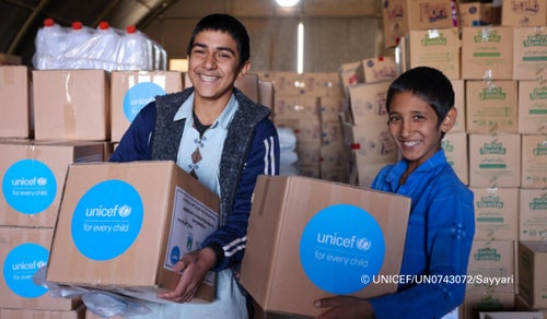 Two Afghan refugee children receive nappy kits for younger members of their families. 