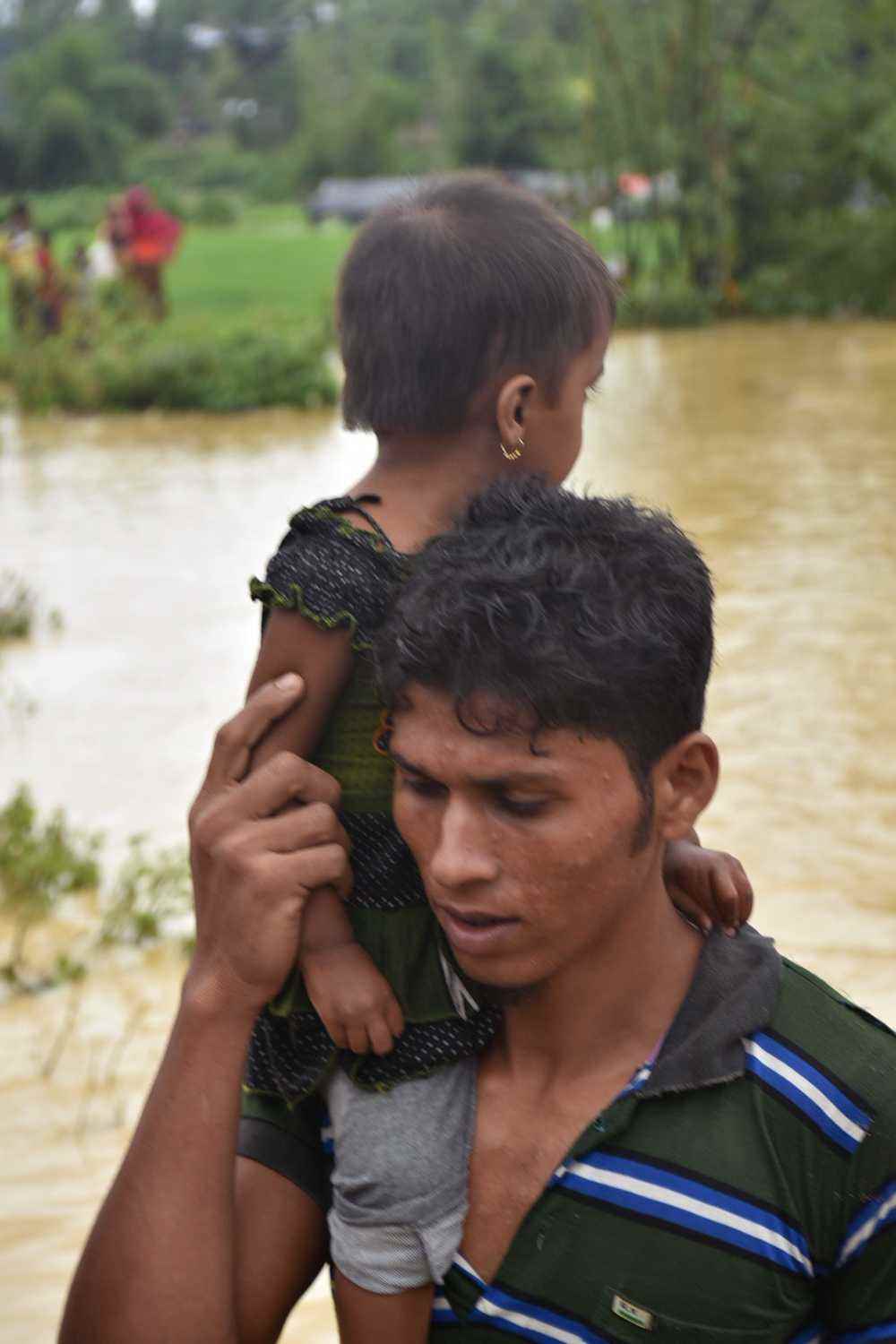 Toyab carries his niece across the river to relative safety / A mother holds her baby closely after evacuating from the flooded camp.