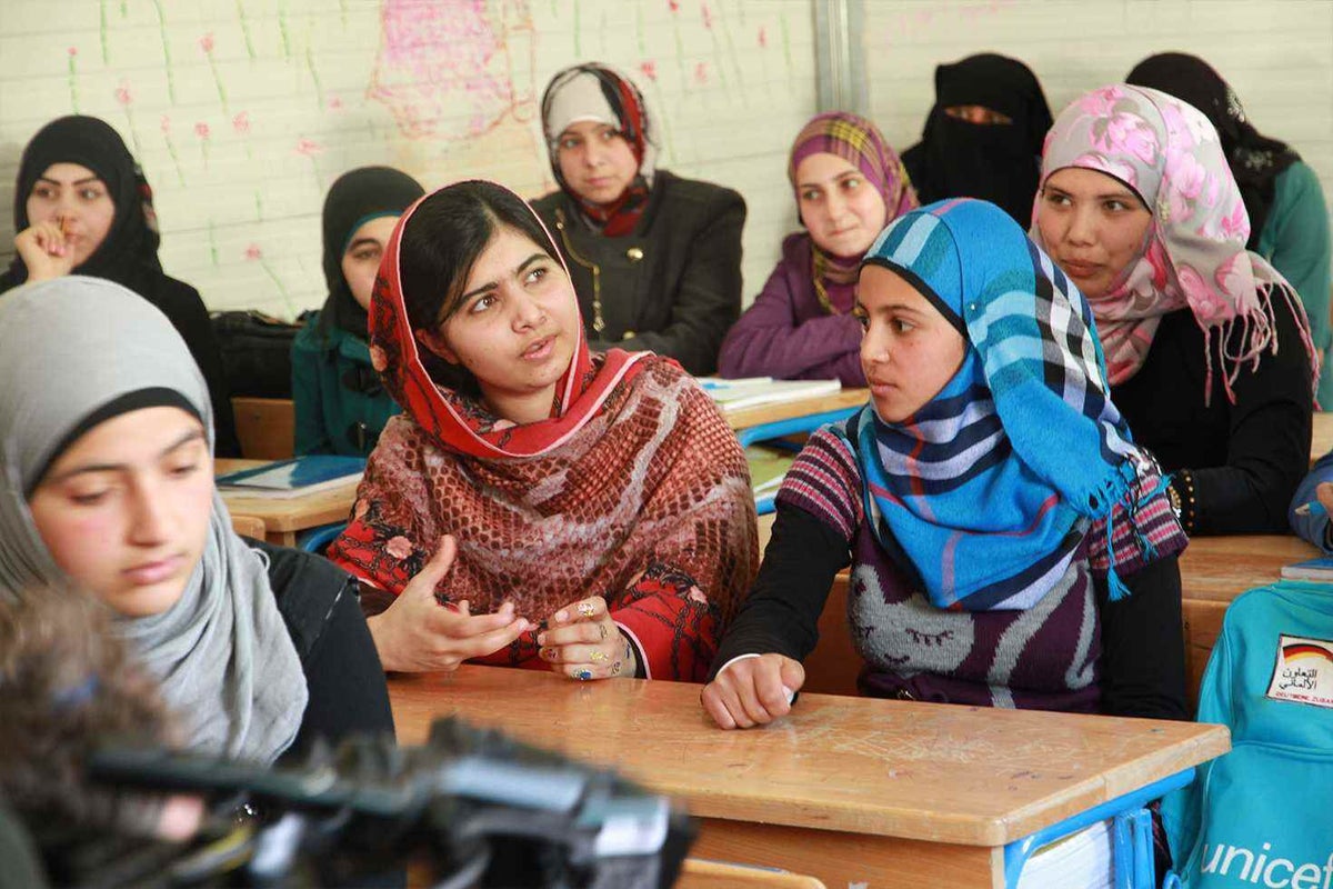 Malala sits next to Muzoon Almellehan in a school in the Za'atari camp for Syrian refugees