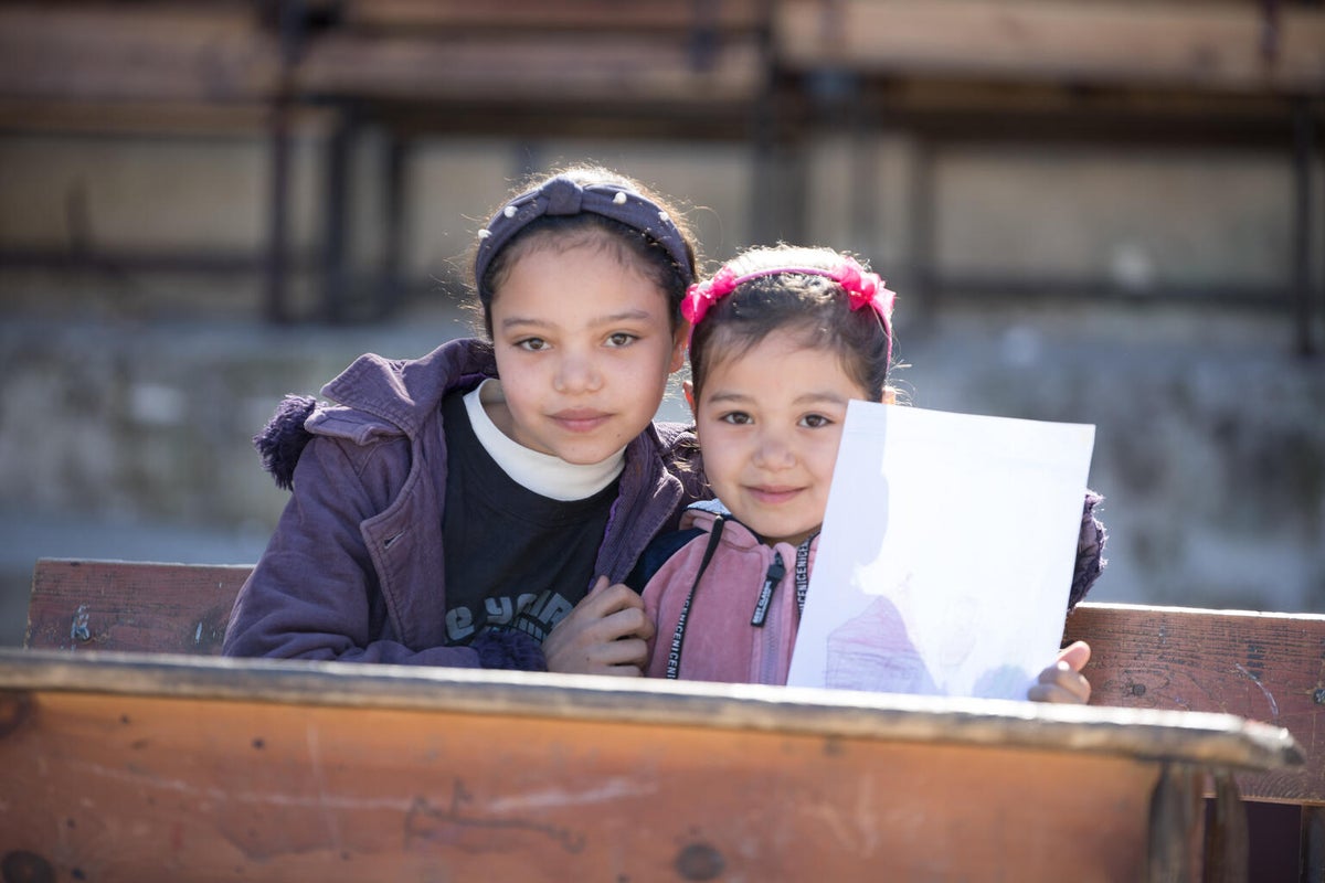 Two sisters hold up a drawing