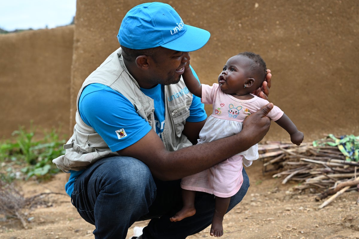 A UNICEF staff member helping a young girl in Cameroon.
