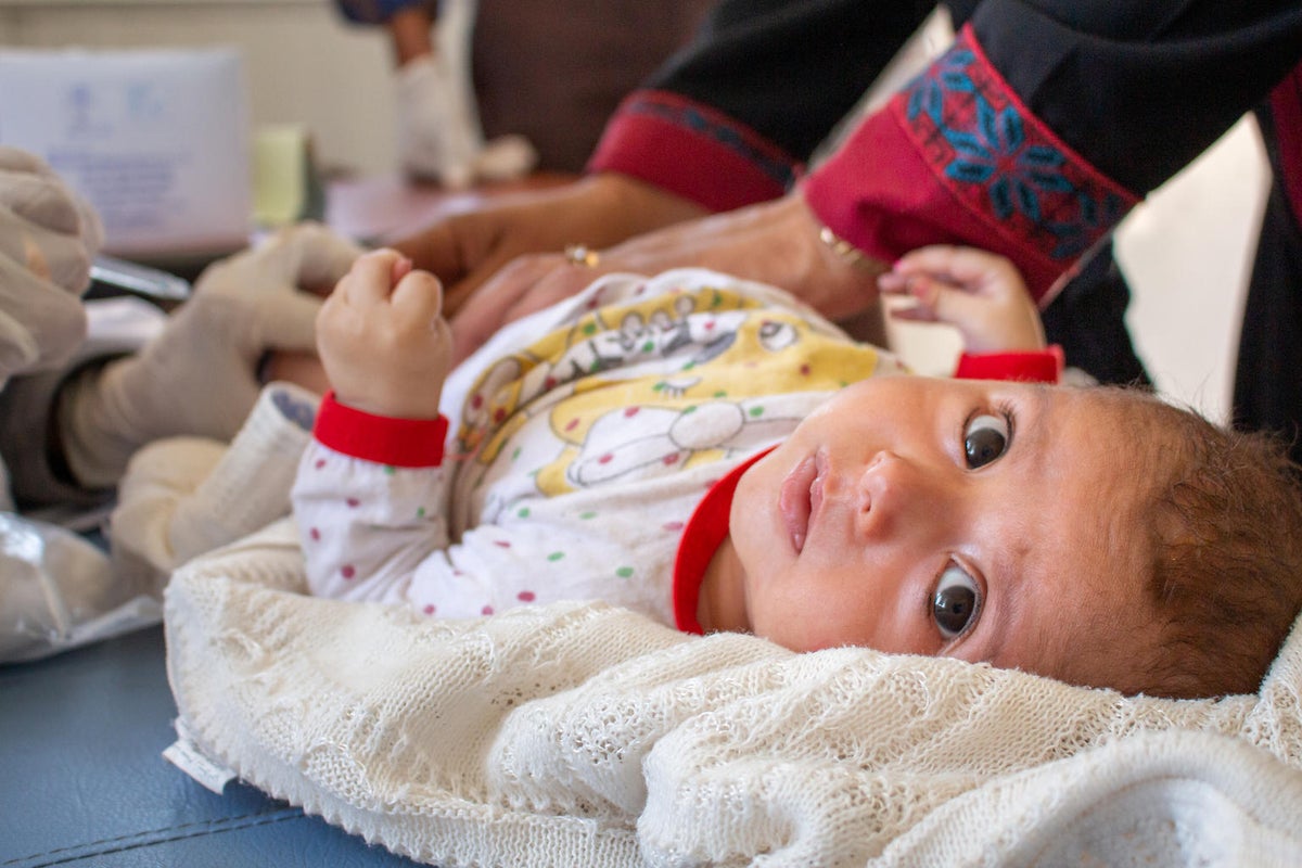 A baby is lying on an table and she is looking at the camera.