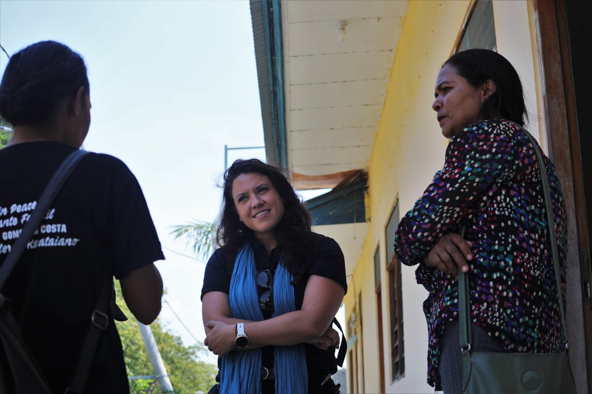 Three women stand talking together in a doorway