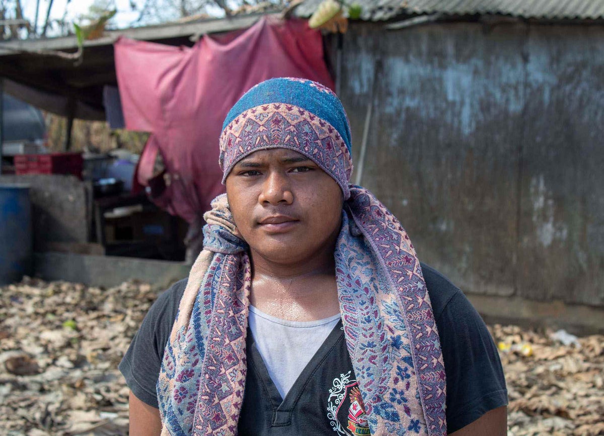 Semisi, 15, stands in front of his home on Tongatapu, Tonga’s main island, with damage caused by the volcanic eruption and tsunami.