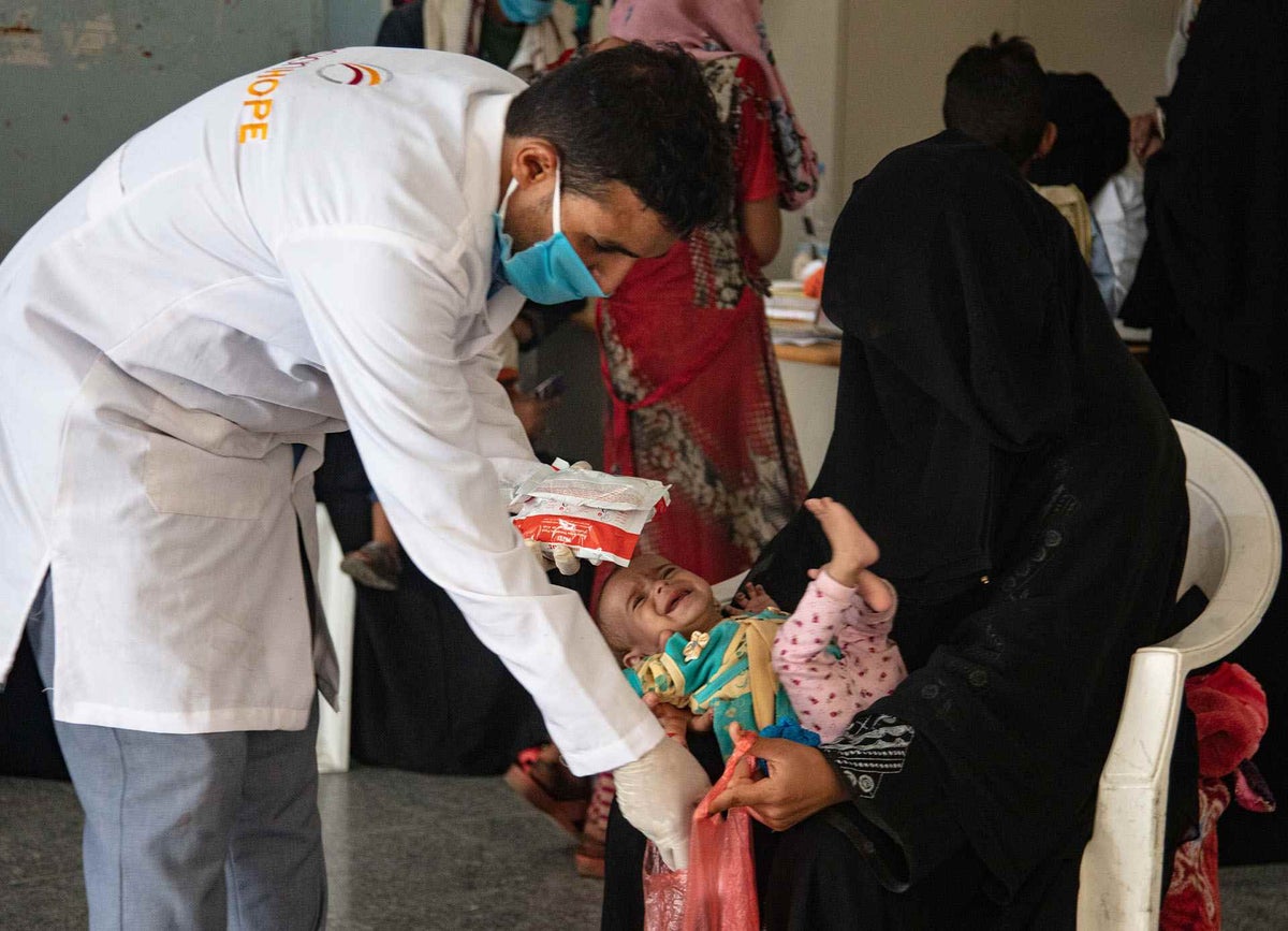 A health worker gives ready-to-use therapeutic food to a mother whose child is suffering from severe acute malnutrition in Yemen. 