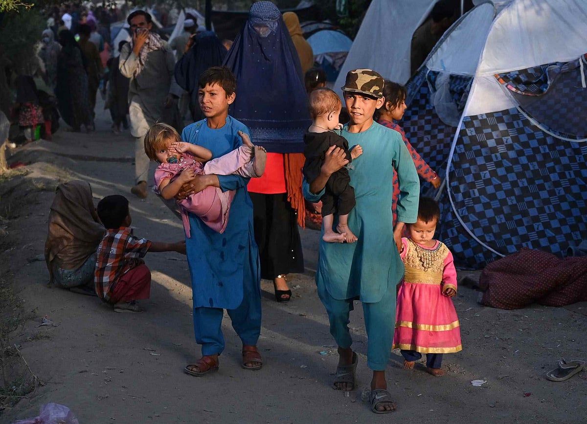 Internally displaced Afghan families walk past their temporary tents in Kabul