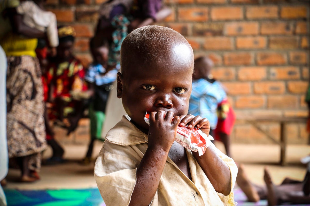 A baby is sucking on a sachet of therapeutic food.