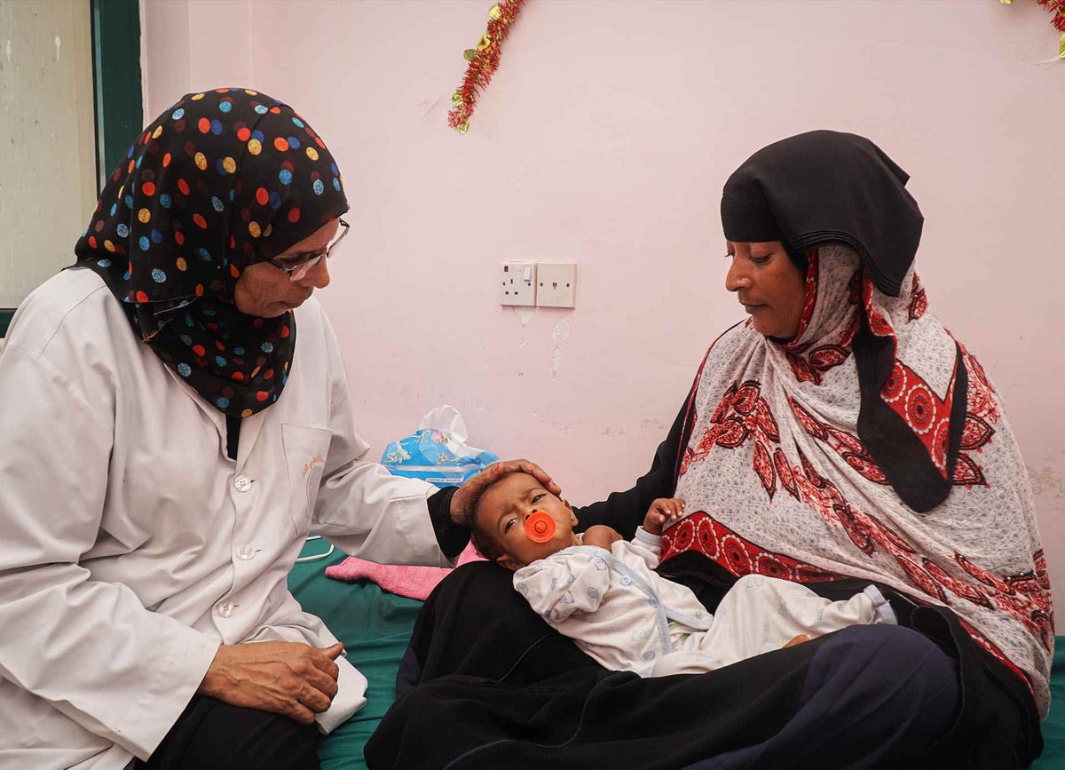 Rahma is held by her mother, Noor, while being examined by the doctor in the severe acute malnutrition treatment centre in Yemen.