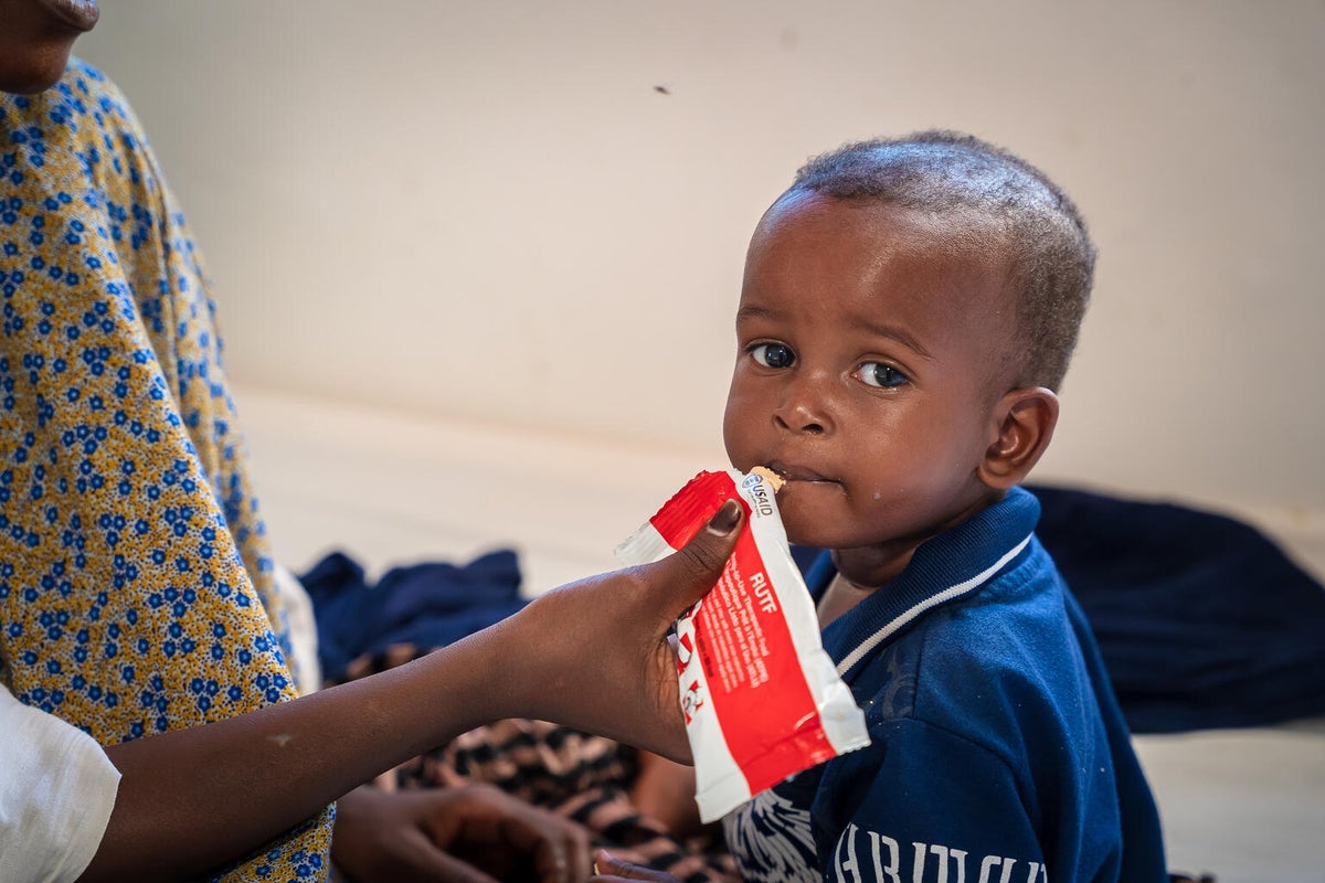 A young boy sucking on a food sachet. 