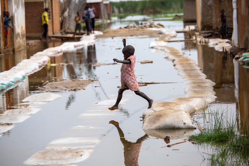 A child in Burundi jumping across flooded streets