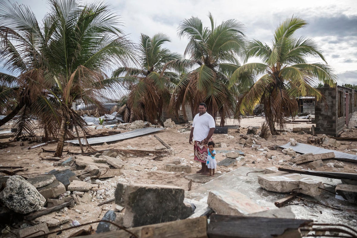 A man and a child are standing on space surrounded by rubble. 