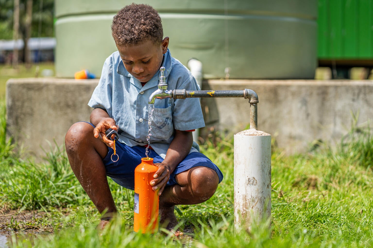 A student fills his water bottle from a UNICEF-supported water supply installation in the Solomon Islands.