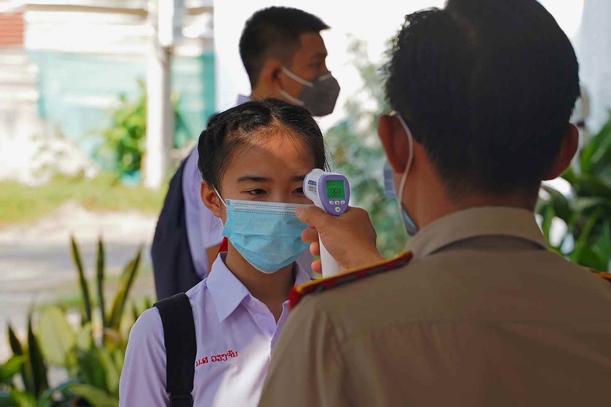 As part of the rules in place to return to school in Laos, children have their temperature checked before entering the school. 
