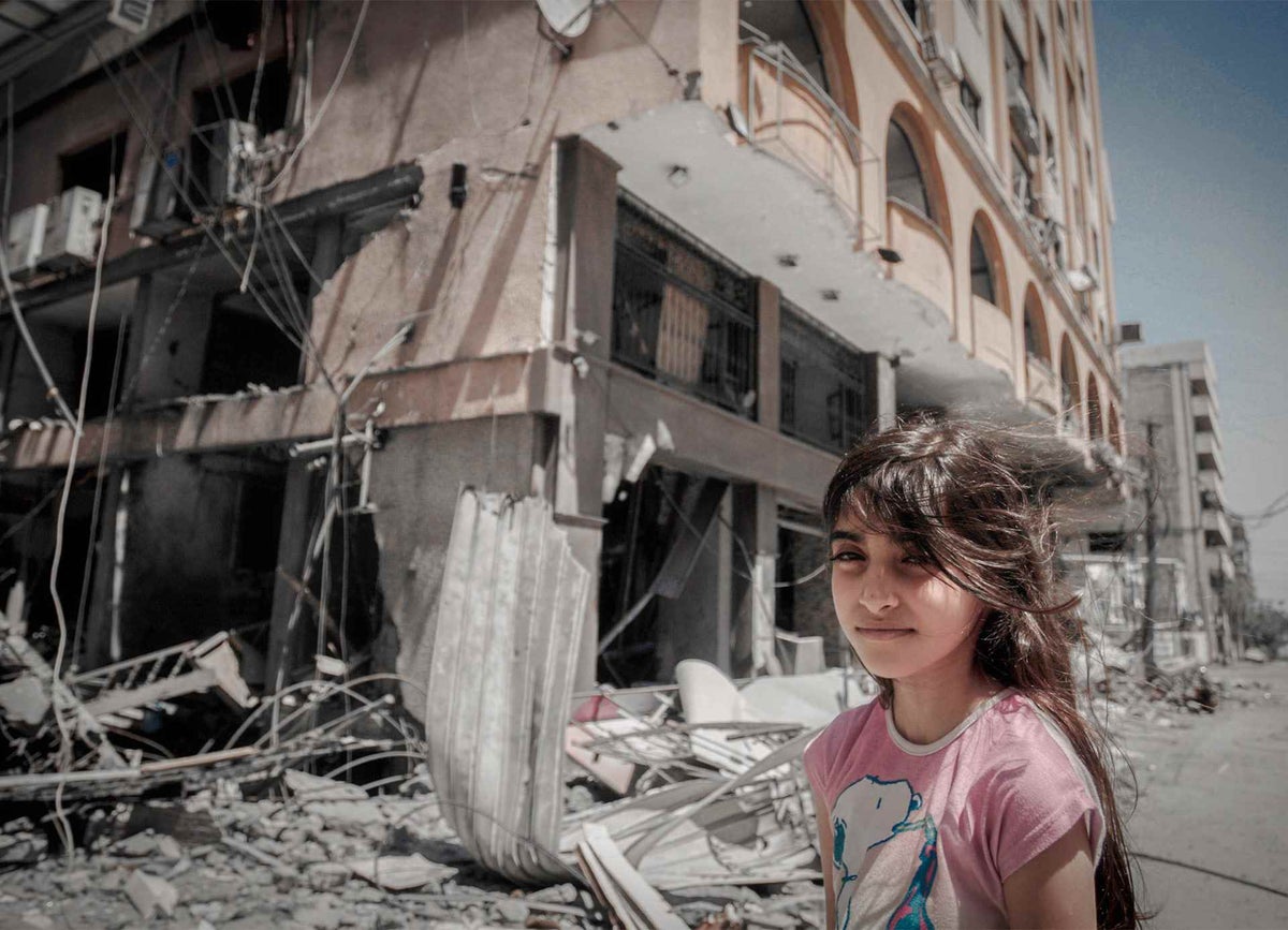A Palestinian girl stands in front of their damaged home in Gaza City.
