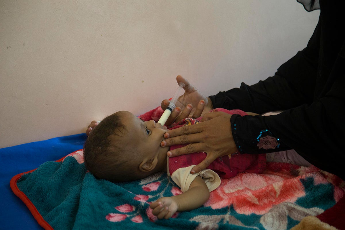 A baby is fed with a syringe that has milk in it.