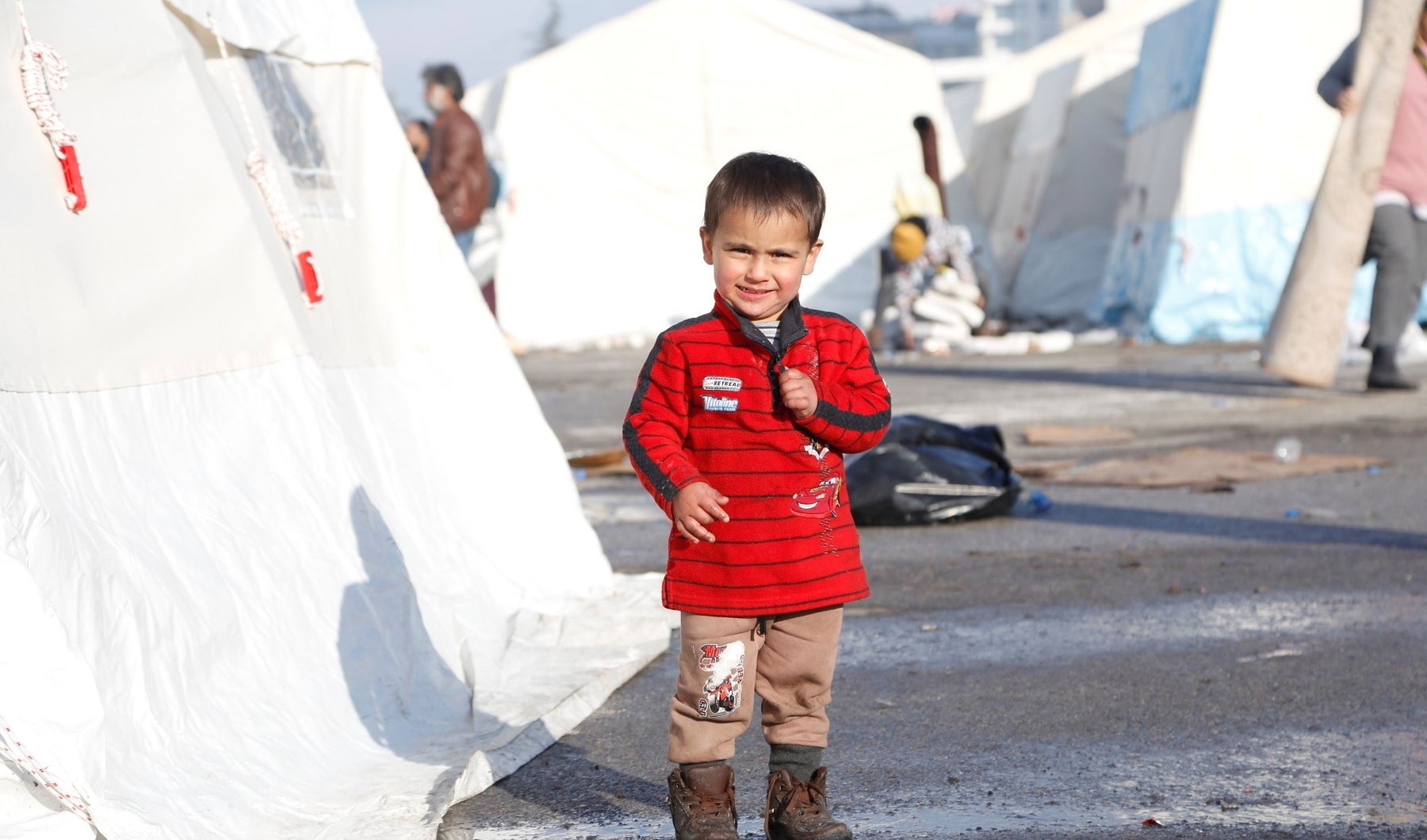 A little boy walking around a temporary shelter, ten days after two devastating earthquakes hit Türkiye.