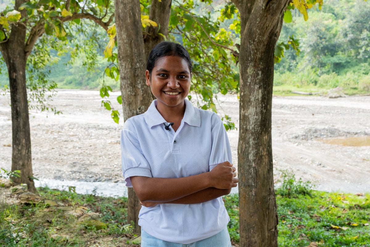 A young smiling woman with her hands folded across her chest.