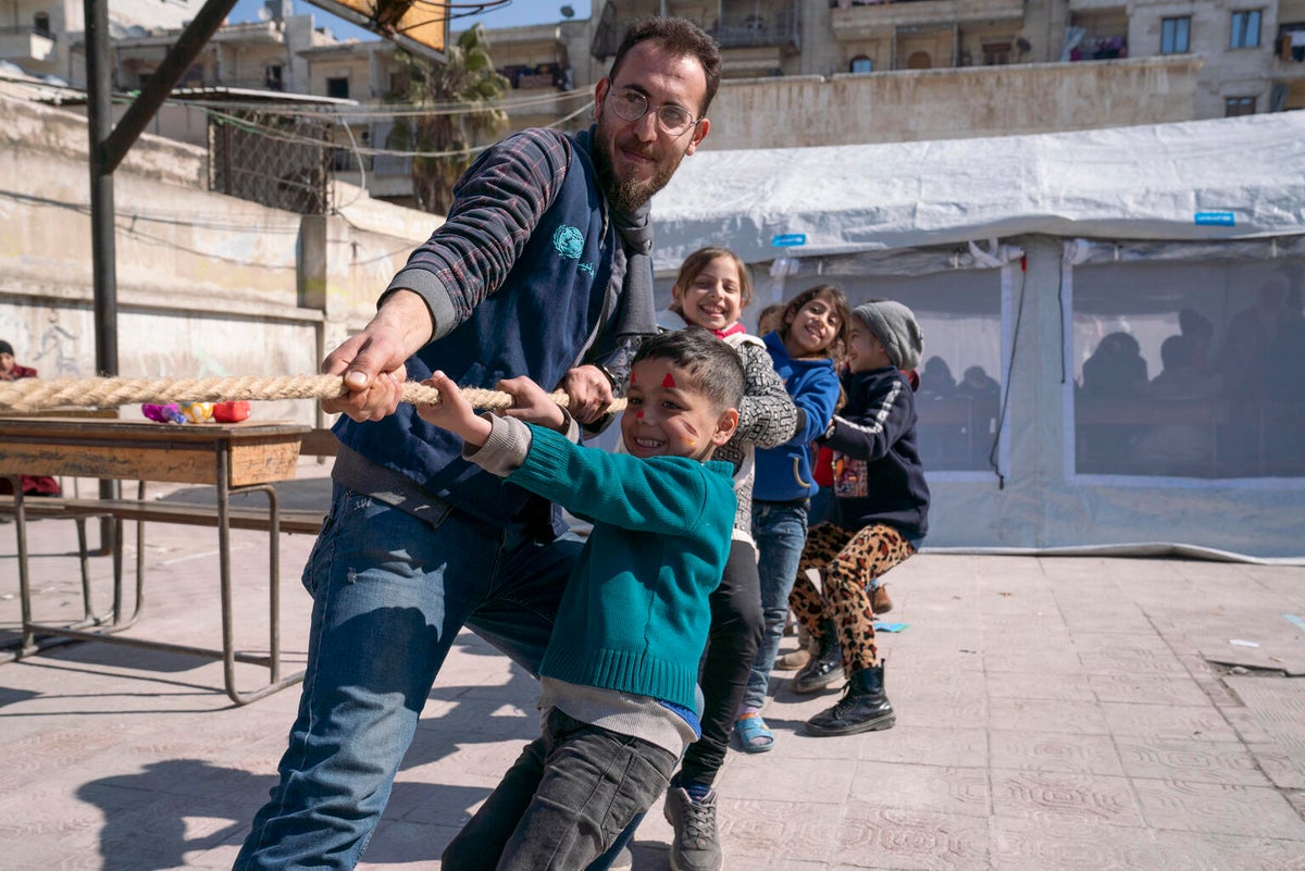 Children play tug of war with UNICEF staff