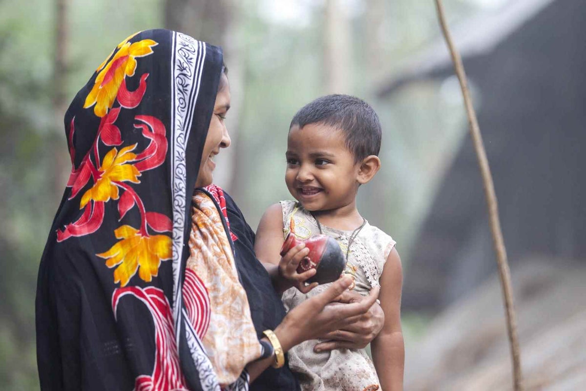 Eanur Begum plays with her daughter Lisa in front of their house in Bhola, Bangladesh in 2014. 