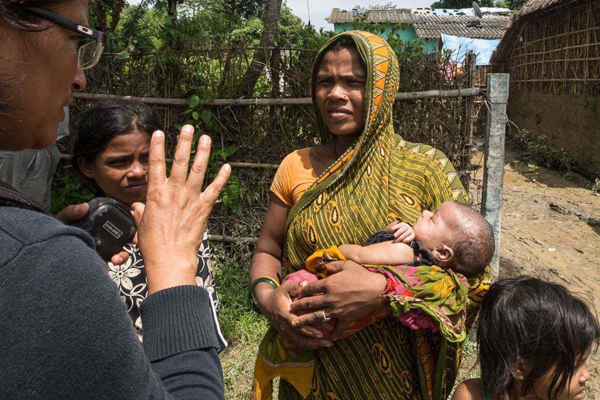 A UNICEF officer speaks to a woman who is holding a baby in her arms.