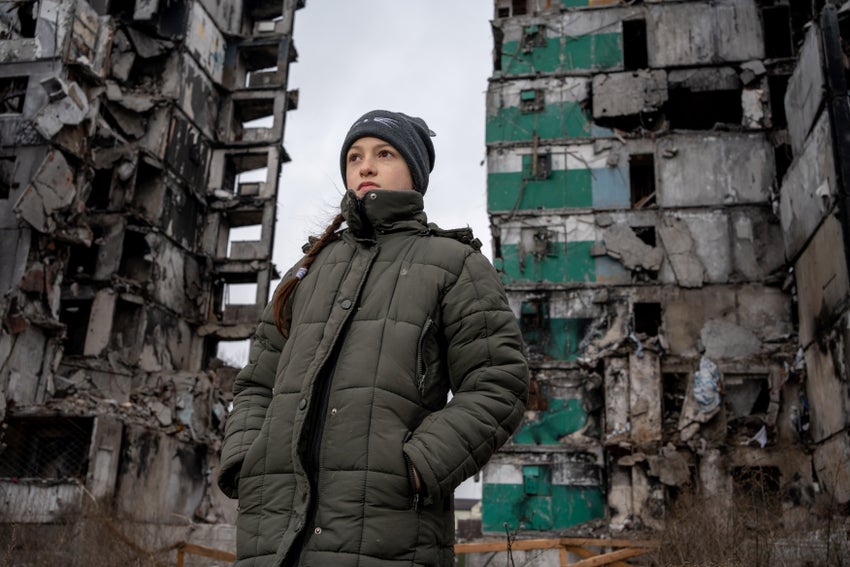 A young Ukraine girl standing out the front of destroyed building.