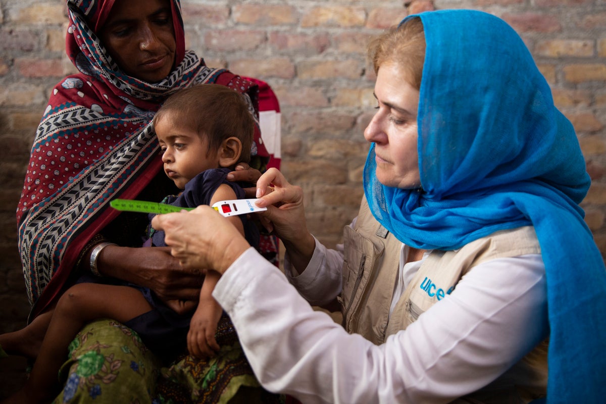 UNICEF staff visits a health centre in a flood-affected area in Pakistan. She performs a mid-upper arm circumference (MUAC) measurement on two-year-old, who is severely malnourished.