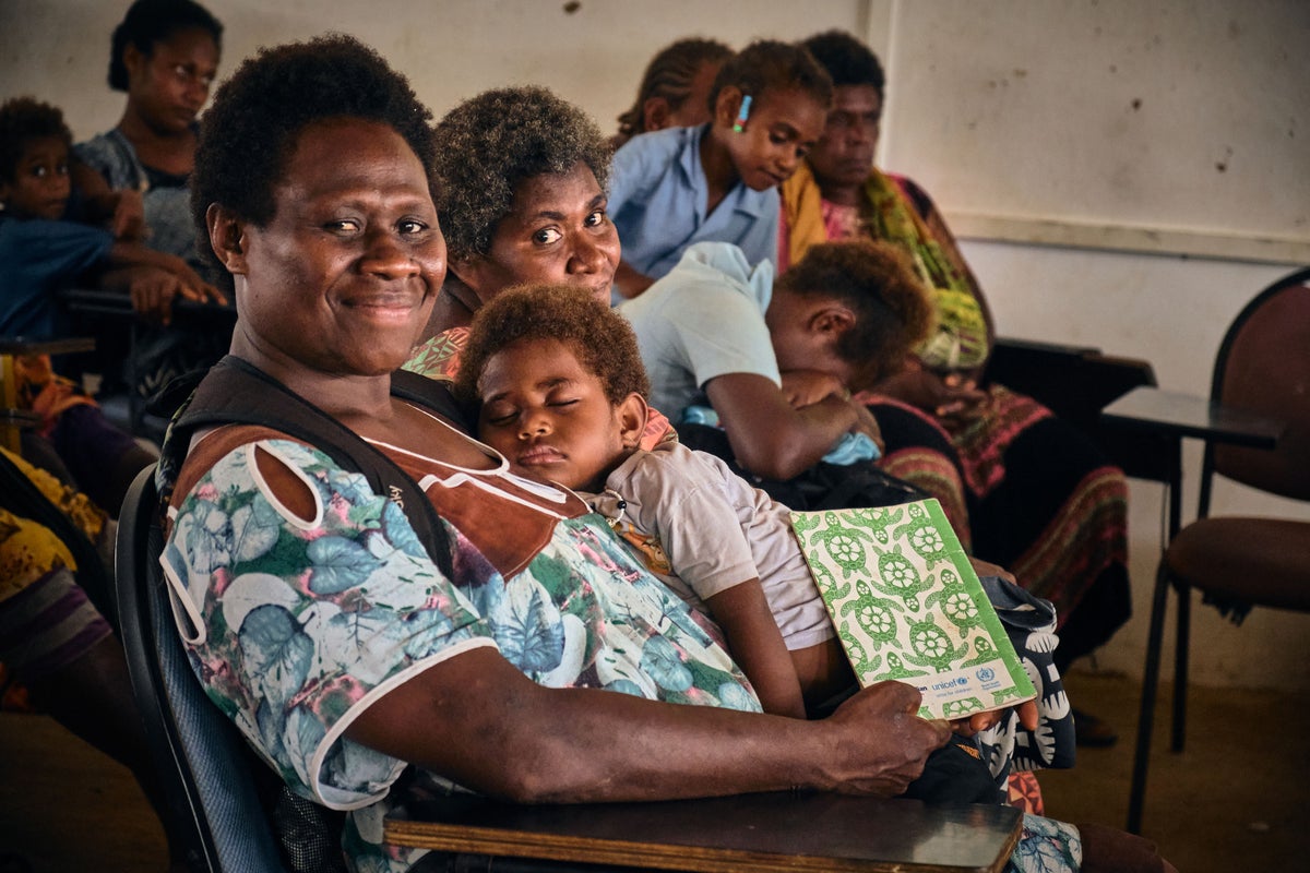 In Vanuatu, a mother waits to get her child checked by health workers.