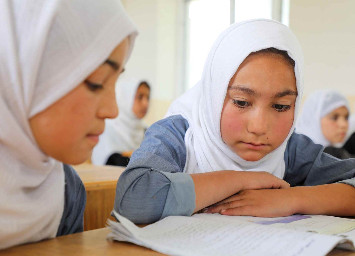 Students read a textbook together at a girls’ high school in Afghanistan after a one-year closure due to COVID-19.