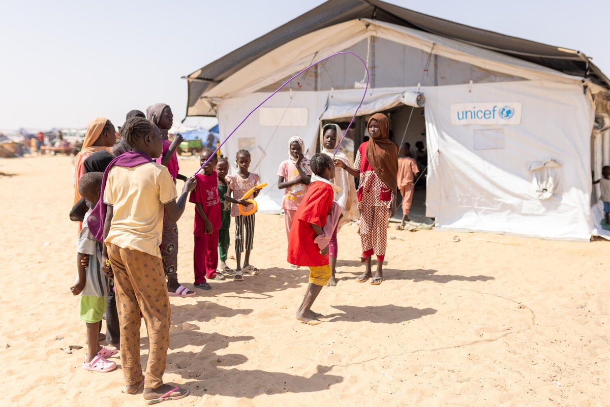 Displaced children play with a skipping rope outside a child-friendly space UNICEF established in Sudan.