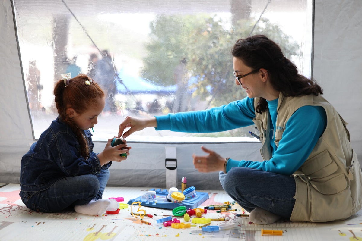 UNICEF worker is playing with Viktoria, who was displaced from Karabakh, in a child corner established by UNICEF Armenia in Goris, while her parents are registering in the State Humanitarian station.
