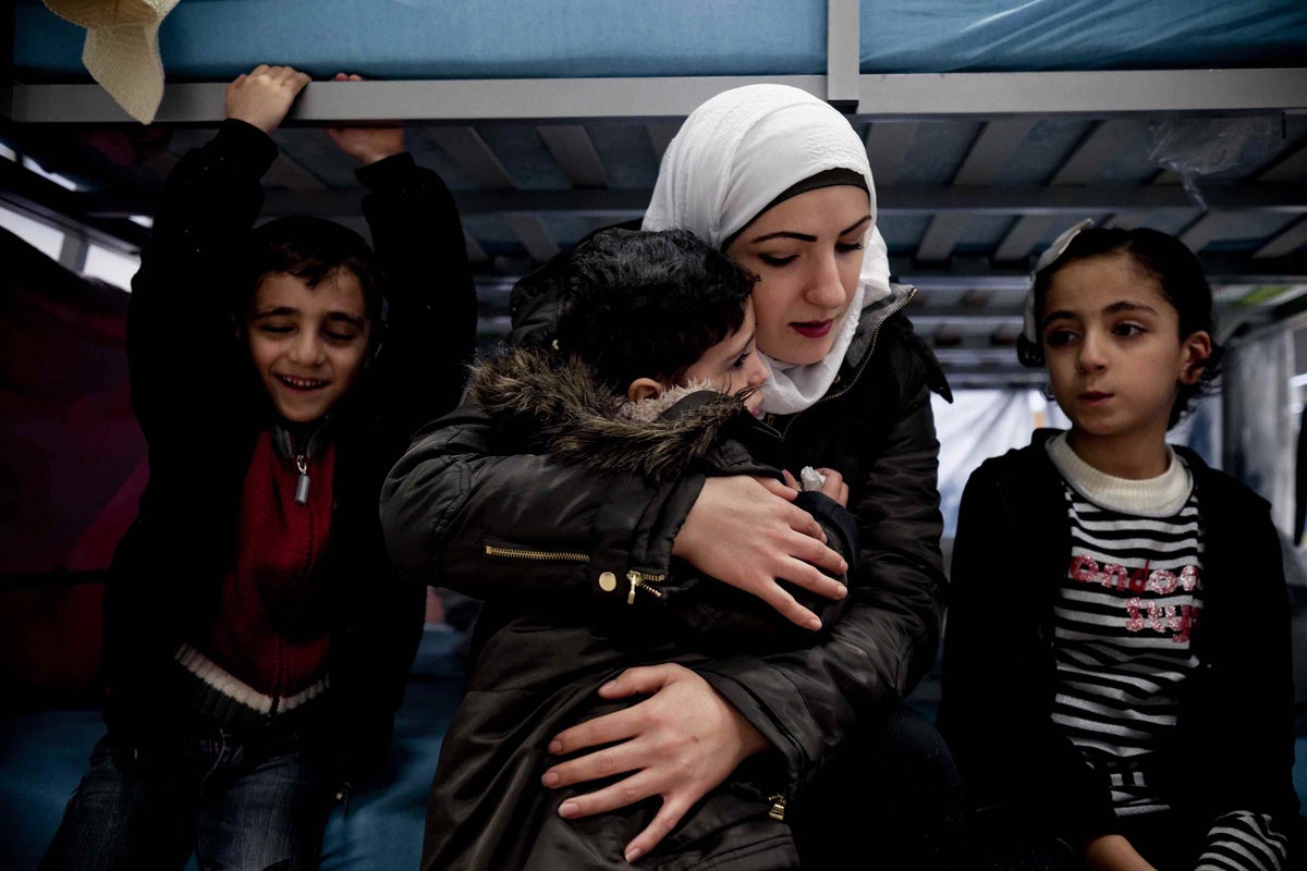 Amira Rasland comforts her crying son Karam in an emergency shelter on the southern edge of Berlin. Beside her are her two other children, Amr and Jannat.