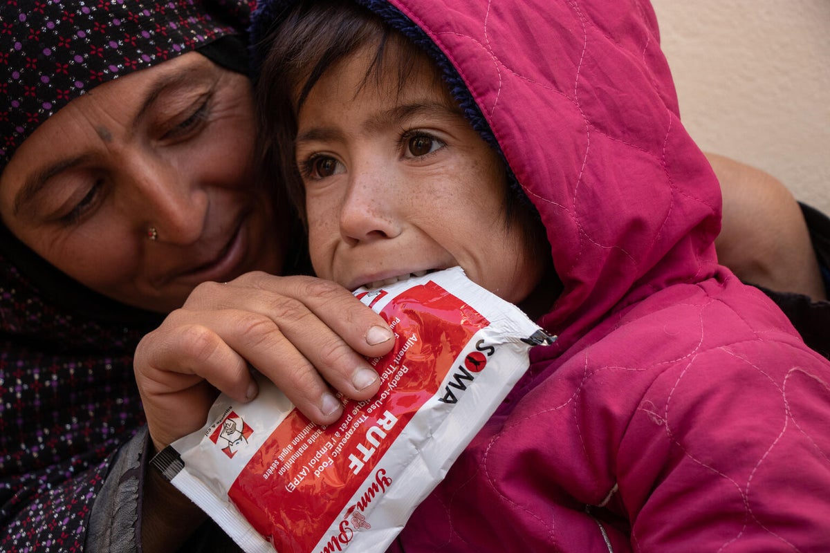 A young girl is sucking a sachet of therapeutic food.