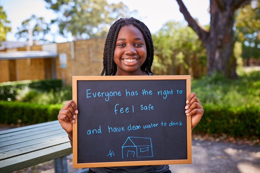 A young girl holding a sign that says that everyone has the right to feel safe.