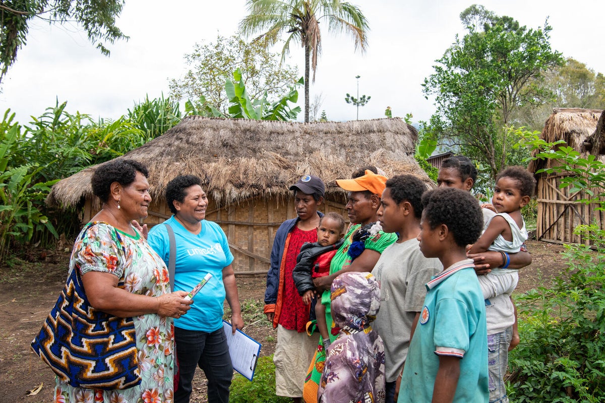 A UNICEF team member talks to a family in a remote village in Papua New Guinea about the national polio vaccination campaign. 
