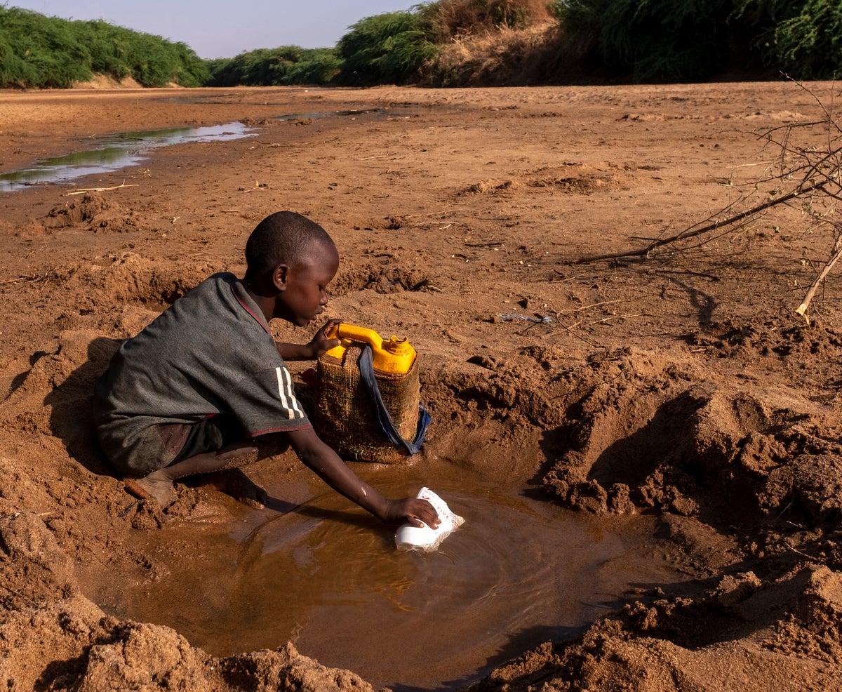 Child collecting water from a puddle in Somalia