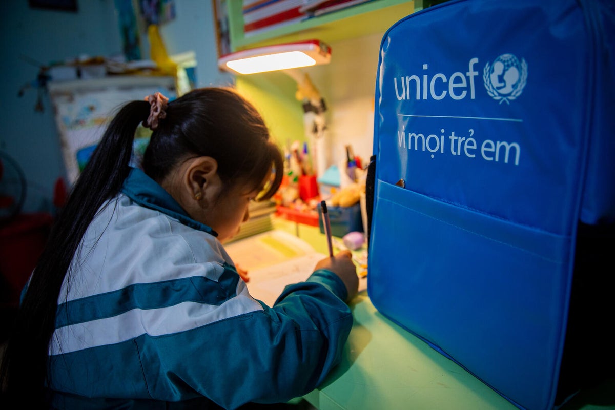 A young girl draws at her desk at home.