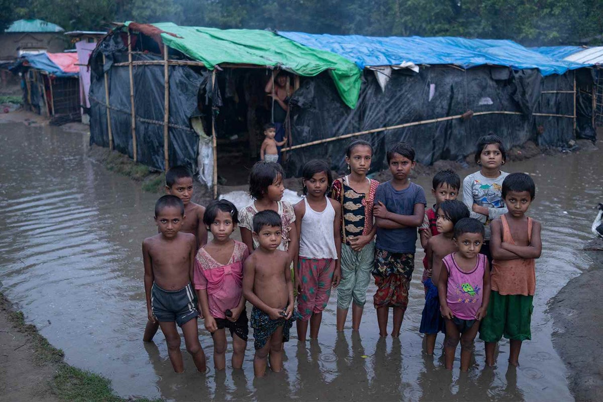 Rohingya children wade through floodwaters surrounding their shelters after a storm in Cox’s Bazar, Bangladesh