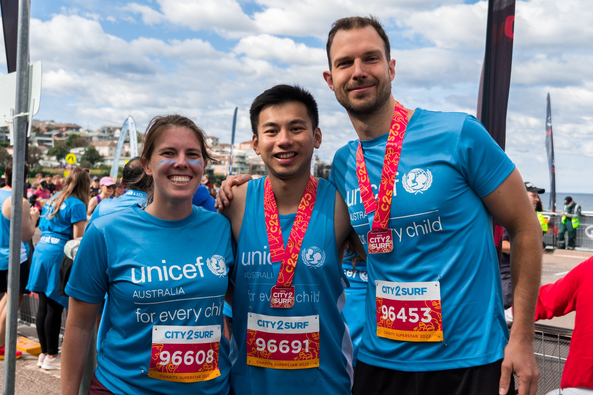 A group of three people wearing UNICEF T-shirts smile.
